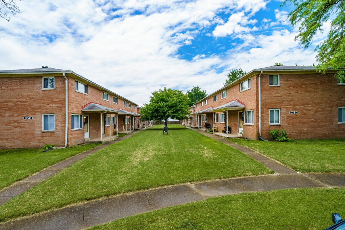 Two-story brick townhome buildings facing a shared lawn courtyard