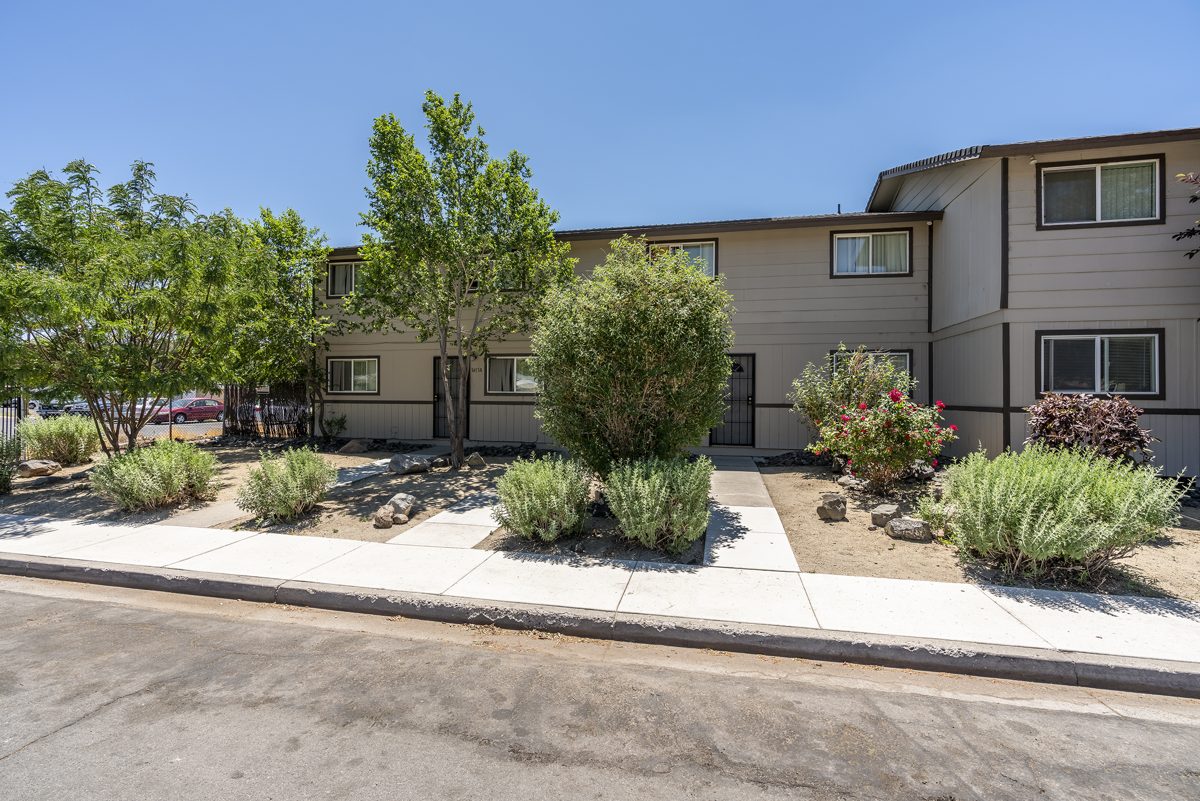 Two-story apartment building with desert landscaping along a sidewalk