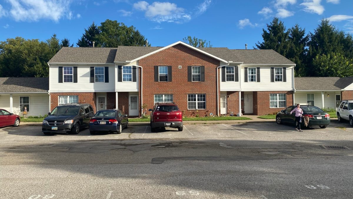 Brick and vinyl townhome building with parking in front
